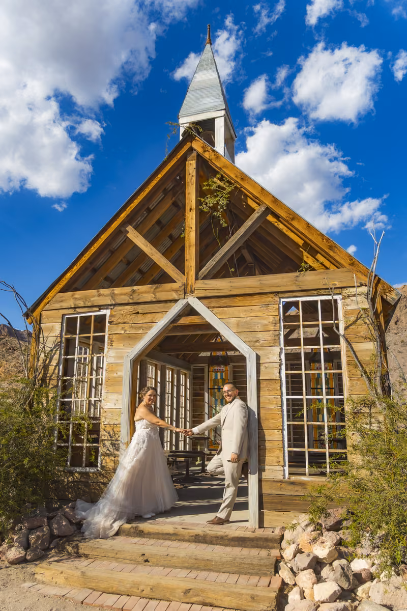 Couple on the steps of the wooden chapel at Nelson Ghost Town under a blue desert sky