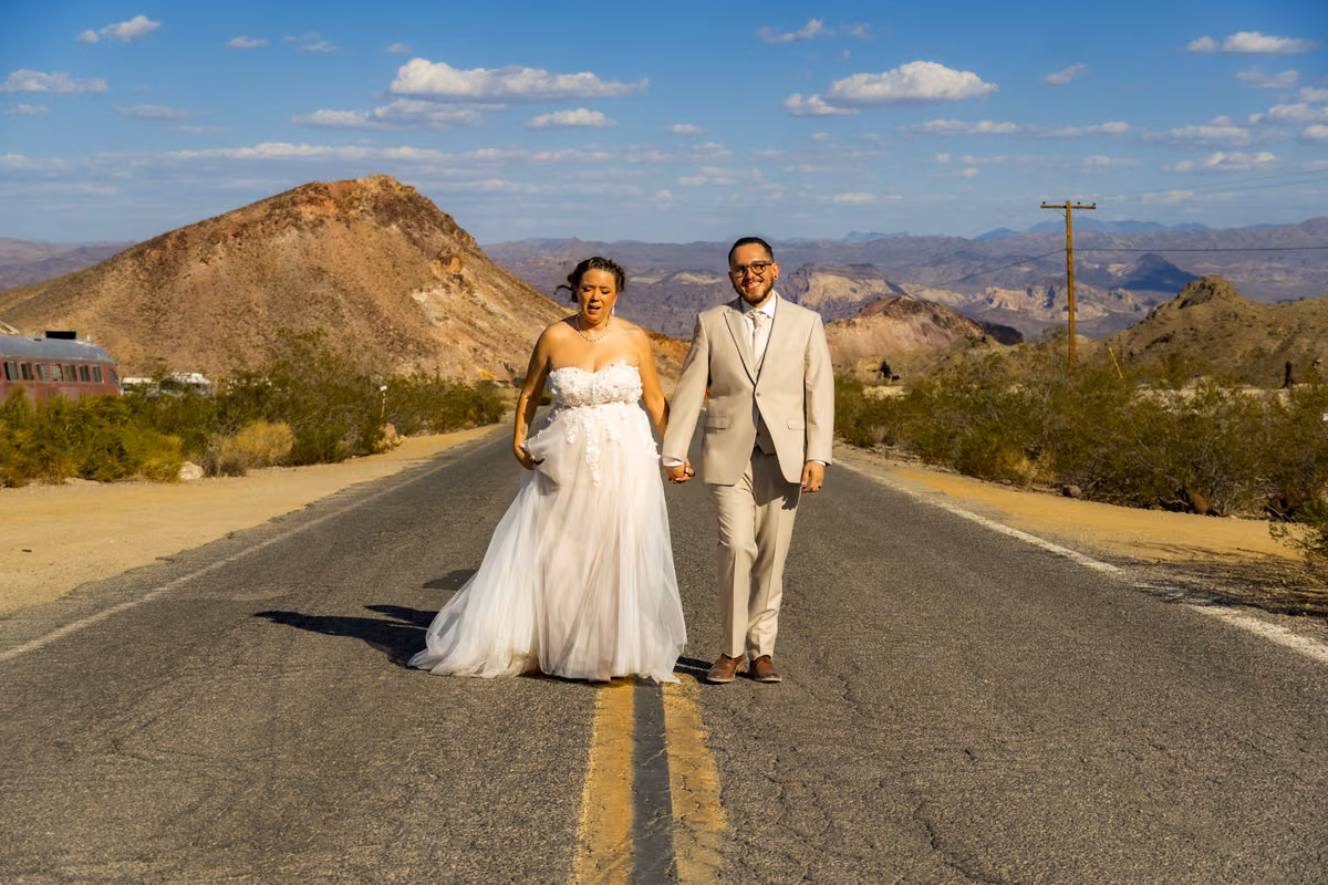 Bride and groom walking down an empty desert highway near Nelson Ghost Town